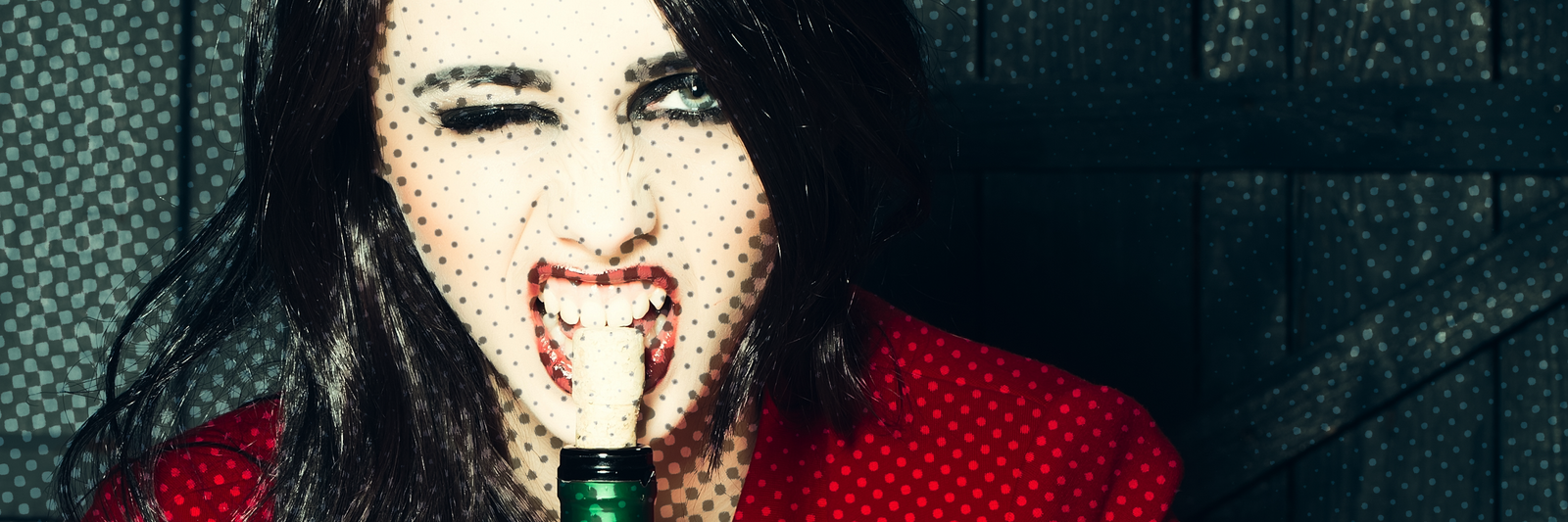 Woman biting on wine cork while winking